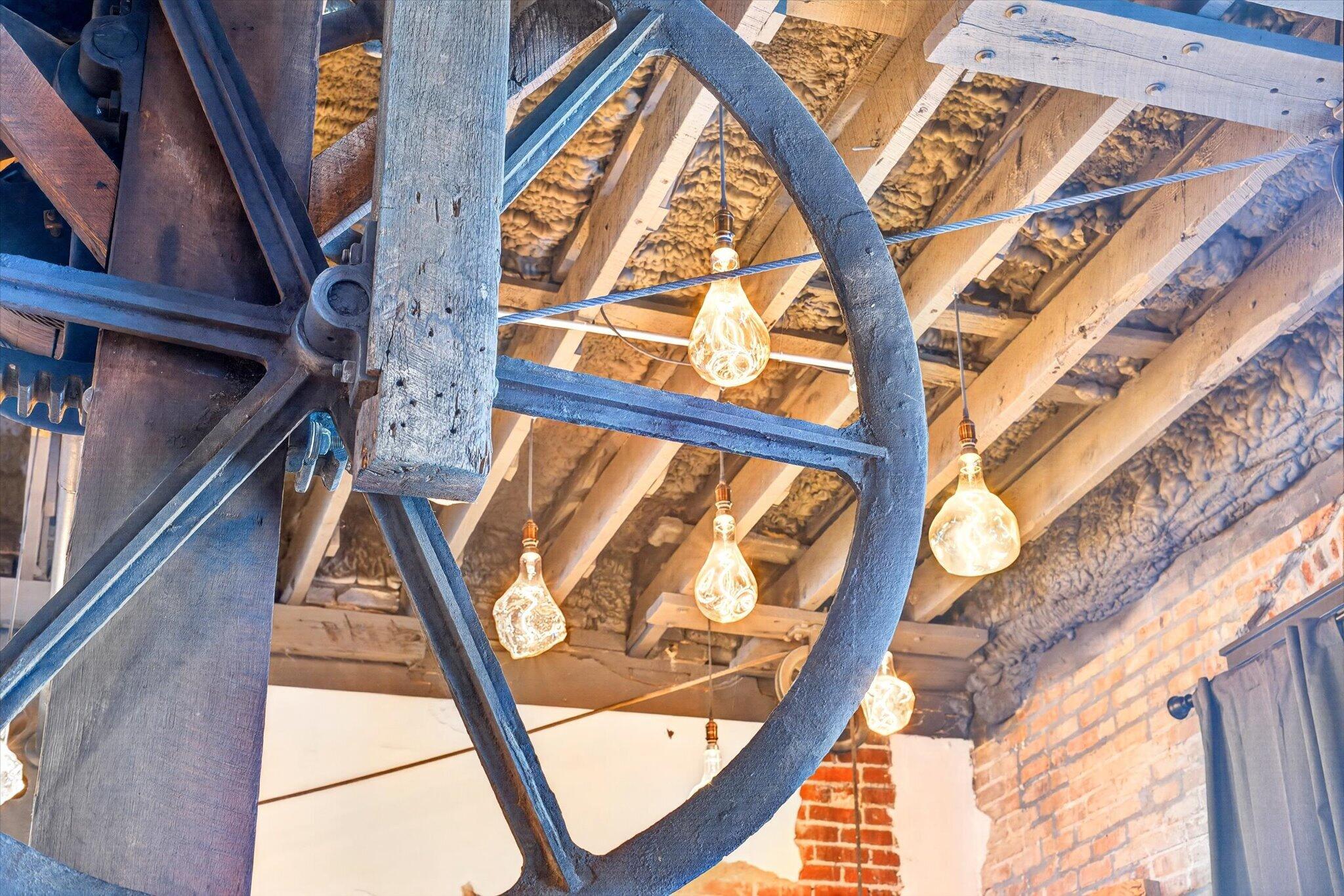 Close-up of the original iron elevator wheel, timber support, and exposed ceiling beams
