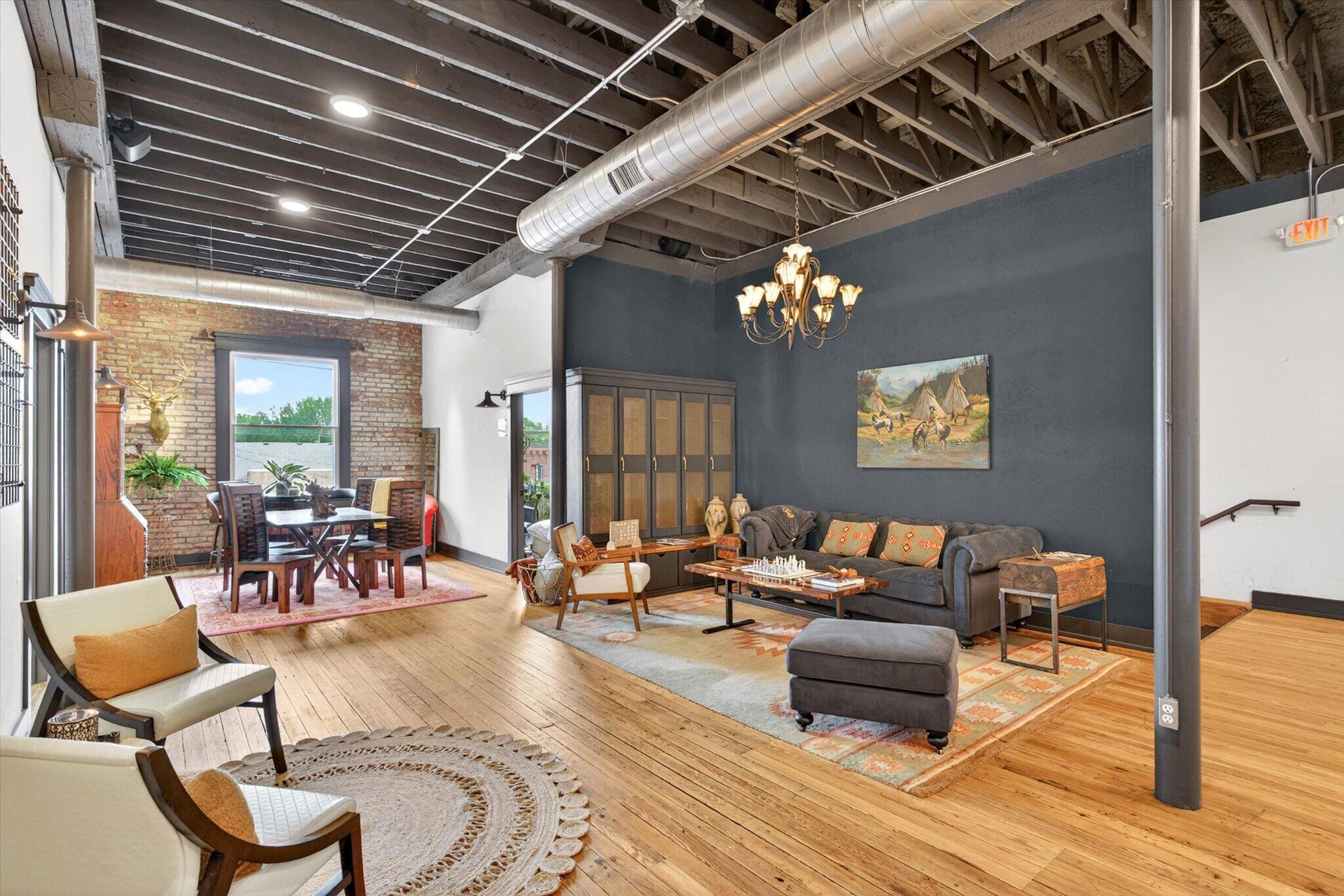 Lounge with a sofa, armchairs, chandelier, and a table beside the Main Street window